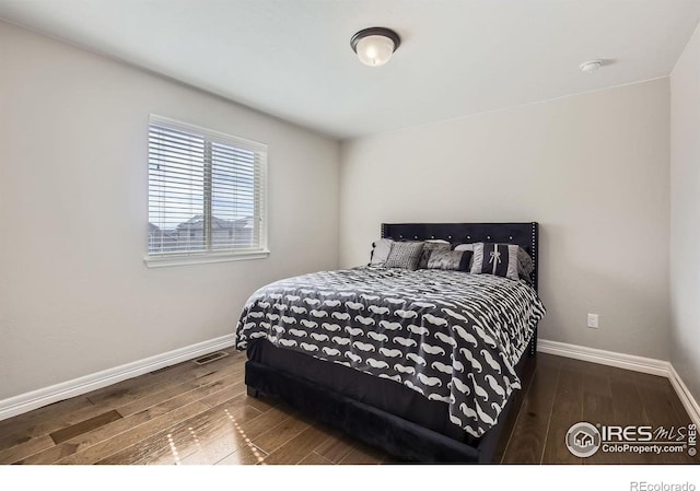 bedroom with wood finished floors, visible vents, and baseboards