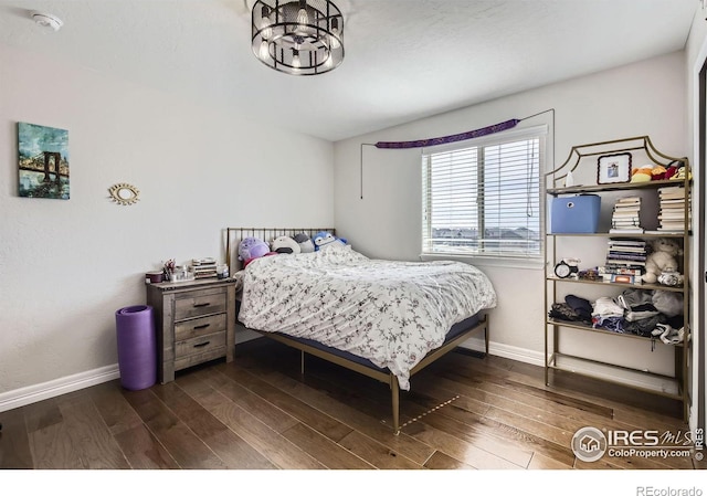 bedroom featuring an inviting chandelier, baseboards, and wood finished floors