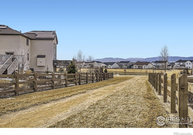 view of yard featuring a residential view, fence, and a mountain view