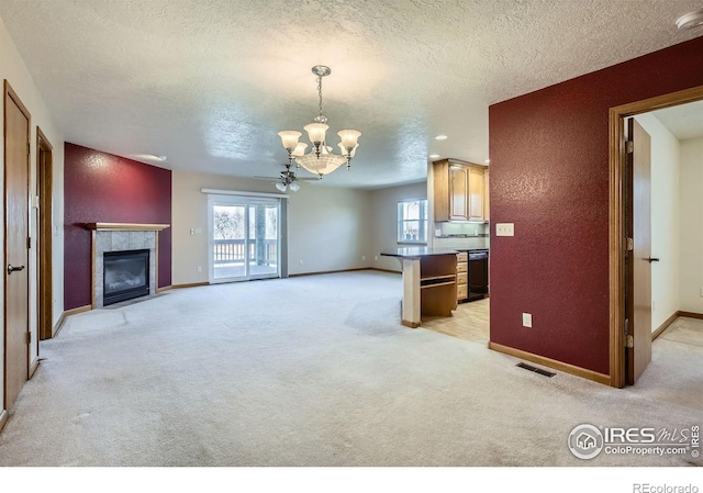 living room featuring a notable chandelier, a fireplace, light colored carpet, a textured wall, and visible vents