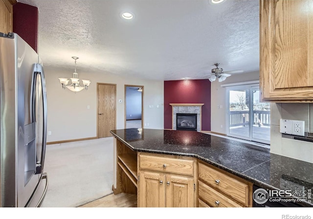 kitchen featuring a tiled fireplace, stainless steel fridge with ice dispenser, a peninsula, a textured ceiling, and ceiling fan with notable chandelier