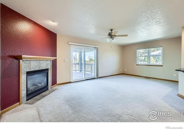 unfurnished living room featuring carpet floors, a healthy amount of sunlight, and a tiled fireplace