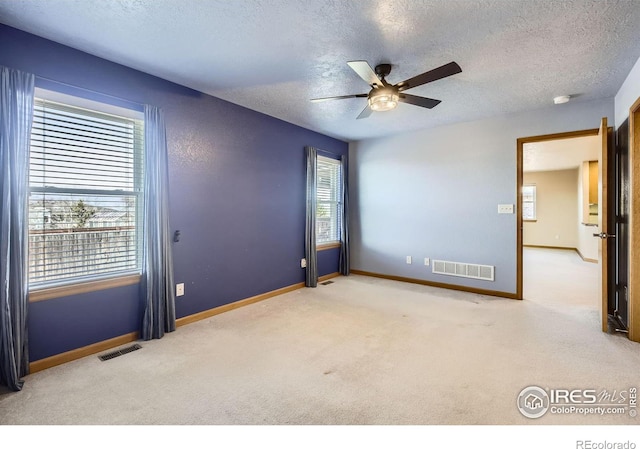 unfurnished room featuring a textured ceiling, carpet floors, visible vents, and baseboards