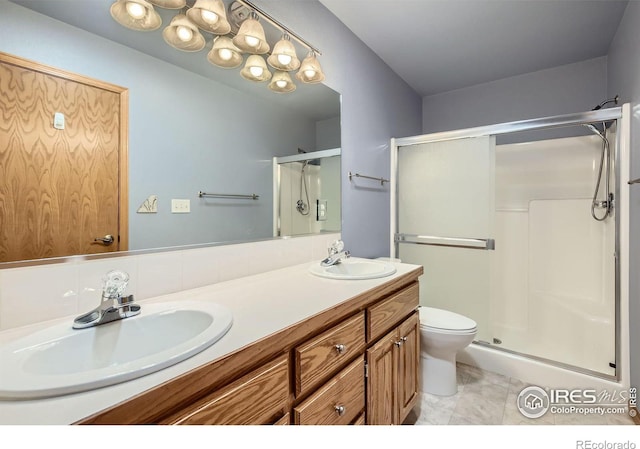 bathroom with a sink, a shower stall, toilet, and double vanity