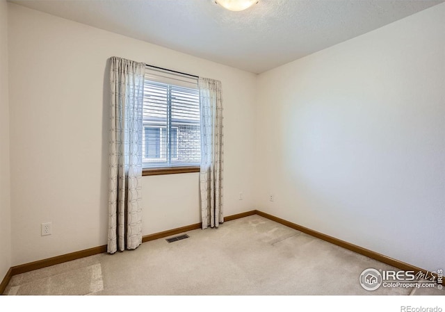 carpeted empty room featuring visible vents, a textured ceiling, and baseboards