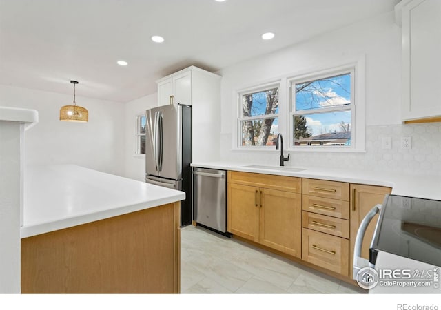 kitchen featuring appliances with stainless steel finishes, hanging light fixtures, a sink, light countertops, and backsplash