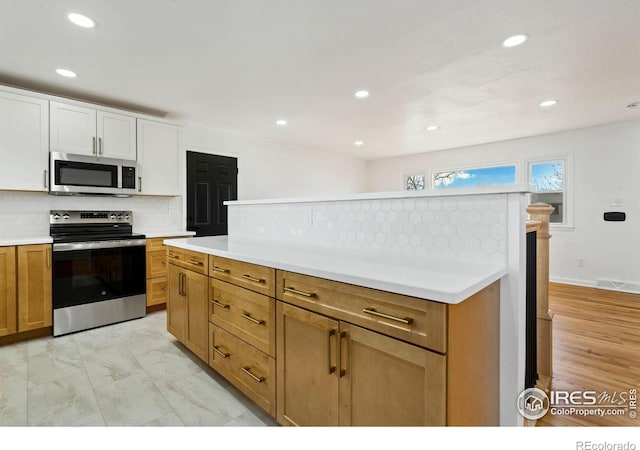 kitchen featuring appliances with stainless steel finishes, marble finish floor, light countertops, white cabinetry, and backsplash