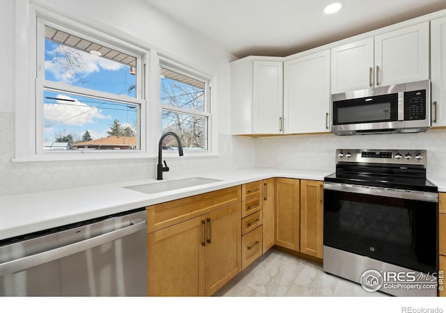 kitchen with decorative backsplash, marble finish floor, stainless steel appliances, light countertops, and a sink