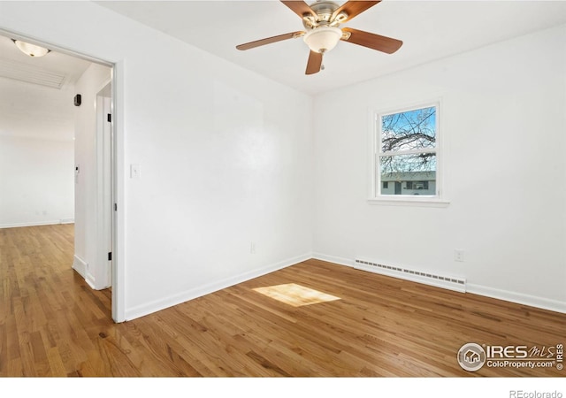 spare room with a baseboard heating unit, baseboards, and wood finished floors