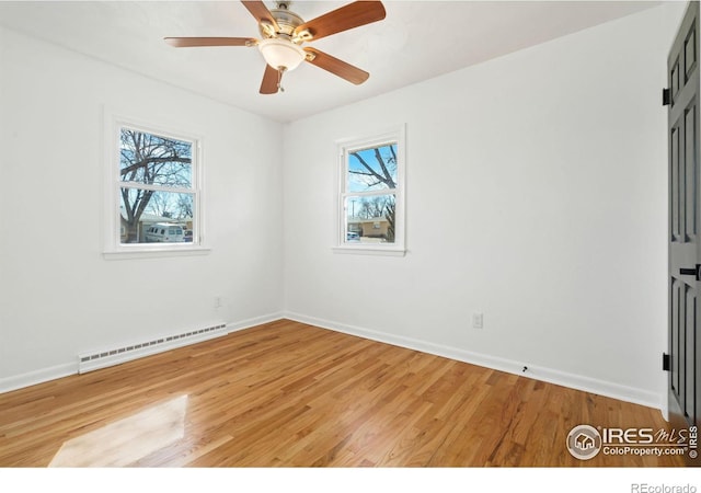 spare room with a baseboard heating unit, light wood-style floors, baseboards, and a ceiling fan