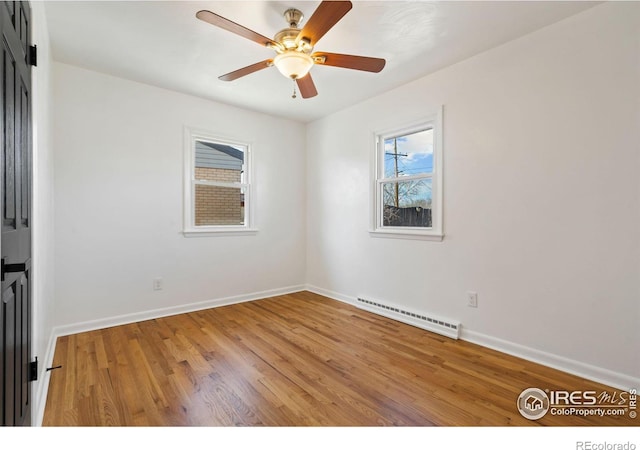 spare room featuring baseboards, ceiling fan, light wood-style flooring, and baseboard heating