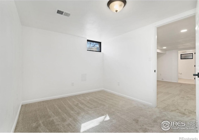 carpeted spare room with visible vents and baseboards