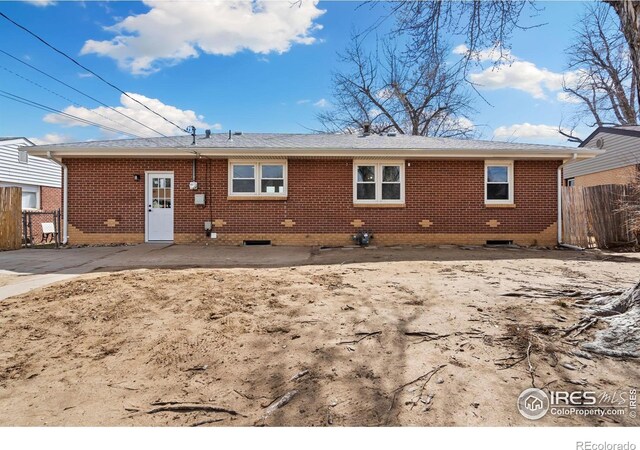 back of house with brick siding and fence