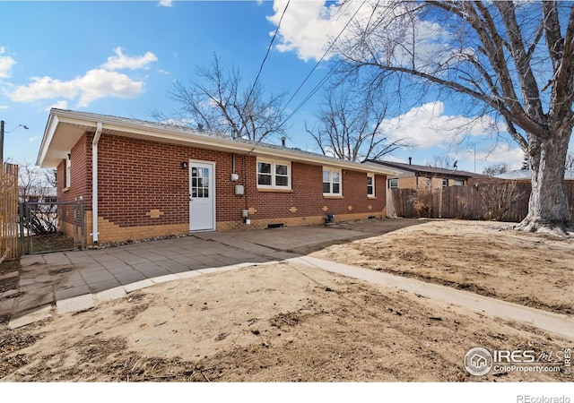 back of property featuring fence, a patio, and brick siding