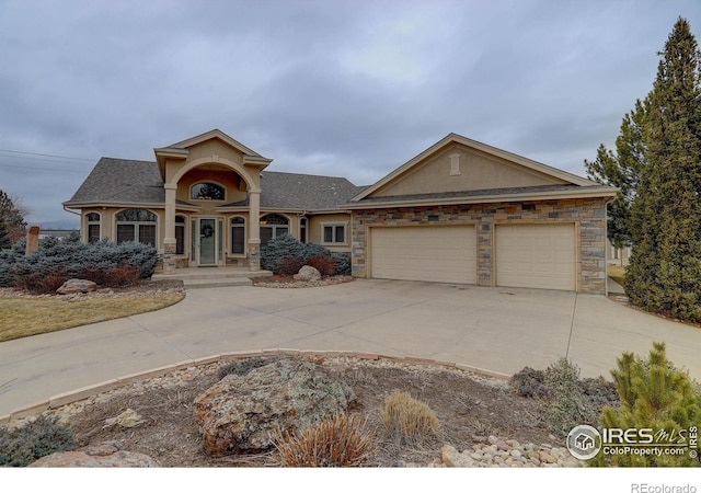 view of front of home featuring a garage, stone siding, concrete driveway, and stucco siding