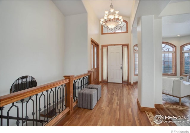 foyer entrance featuring an inviting chandelier, wood finished floors, and baseboards