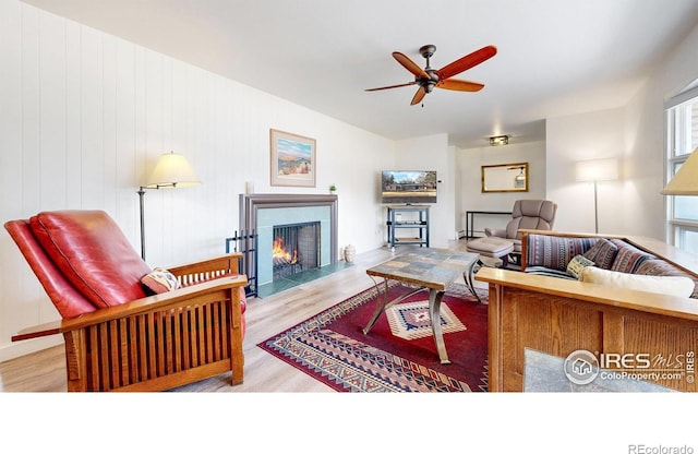 living room with a fireplace with flush hearth, wood finished floors, and a ceiling fan