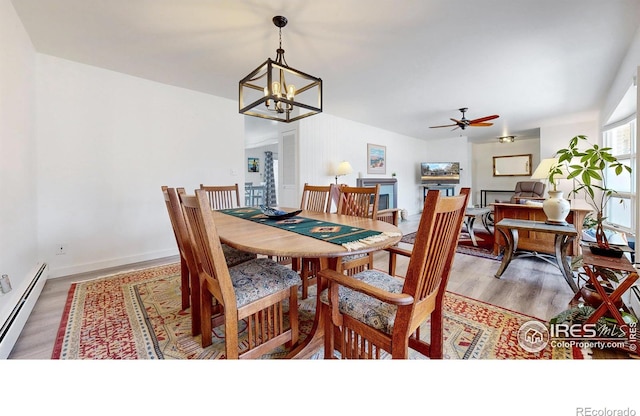 dining space featuring a baseboard heating unit, ceiling fan with notable chandelier, baseboards, and light wood-style floors