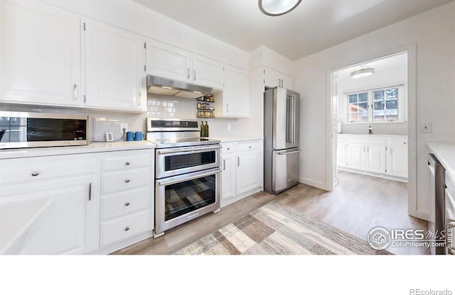 kitchen featuring stainless steel appliances, light countertops, decorative backsplash, white cabinets, and under cabinet range hood