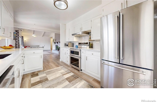 kitchen with appliances with stainless steel finishes, white cabinets, light wood-style flooring, and under cabinet range hood