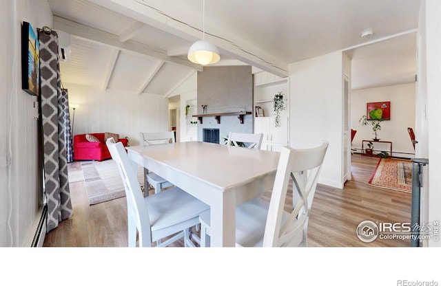 dining space featuring lofted ceiling with beams, a baseboard radiator, and wood finished floors