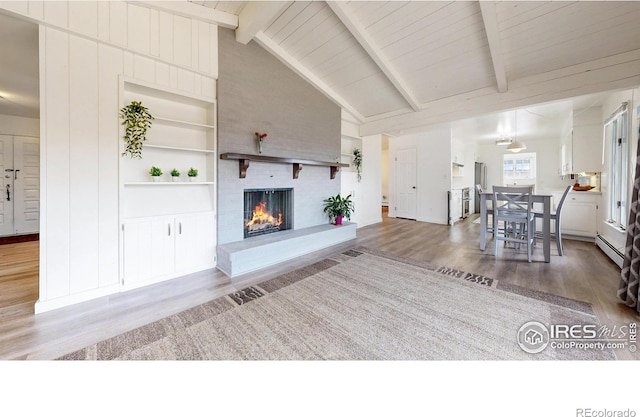 living room with a baseboard heating unit, a fireplace, lofted ceiling with beams, and wood finished floors