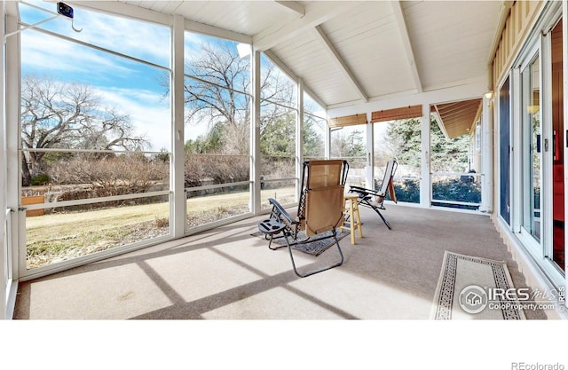 unfurnished sunroom featuring lofted ceiling with beams