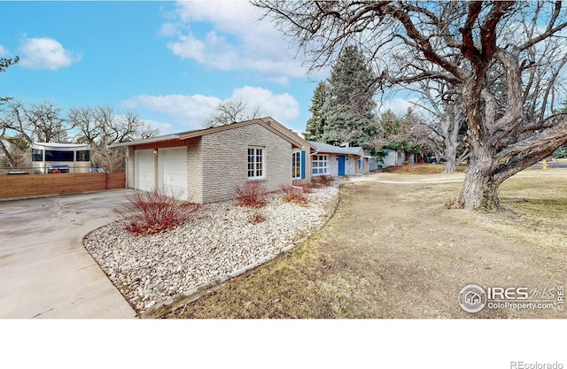 view of property exterior featuring a garage, concrete driveway, brick siding, and fence