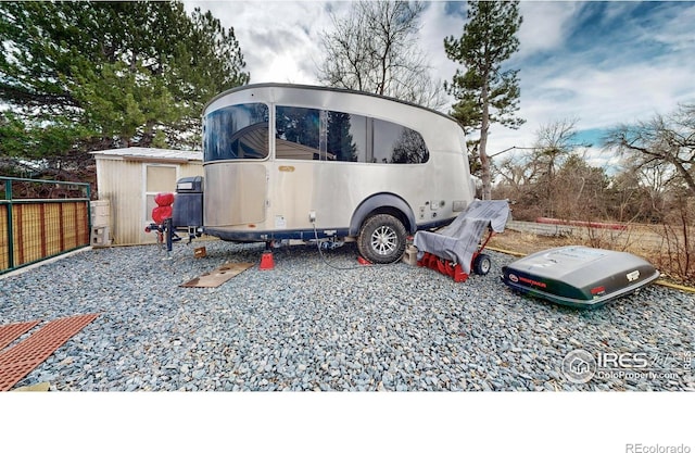 view of parking / parking lot featuring a storage unit and fence