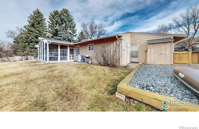 back of property featuring a sunroom, a lawn, and fence