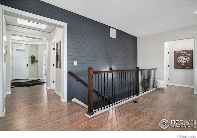 hallway with baseboards, a notable chandelier, an upstairs landing, and wood finished floors