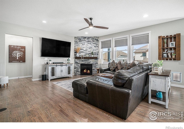 living room featuring a textured ceiling, a large fireplace, and wood finished floors