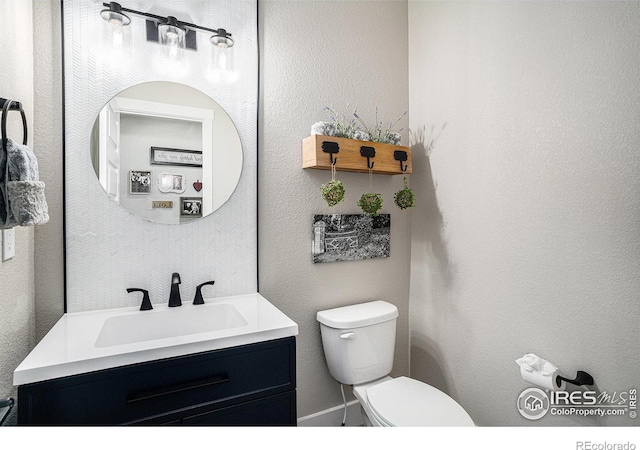 bathroom featuring a textured wall, vanity, and toilet