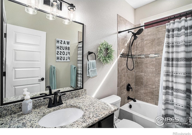 full bath with a textured wall, shower / bath combo, vanity, and toilet