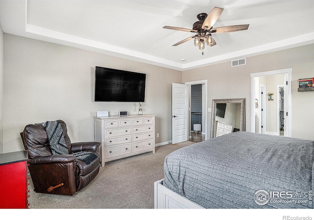 bedroom featuring carpet floors, visible vents, a raised ceiling, and a ceiling fan