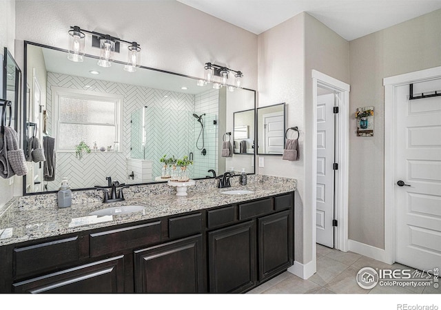 full bathroom featuring a tile shower, double vanity, tile patterned flooring, and a sink