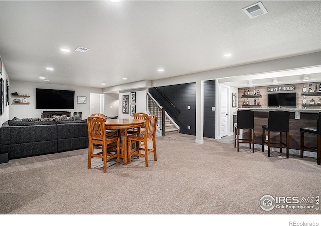 dining area featuring stairs, bar, visible vents, and light colored carpet