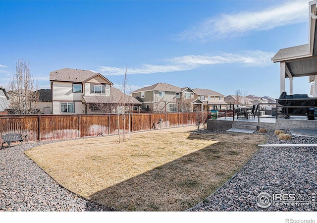 view of yard featuring a fenced backyard, a residential view, and a patio