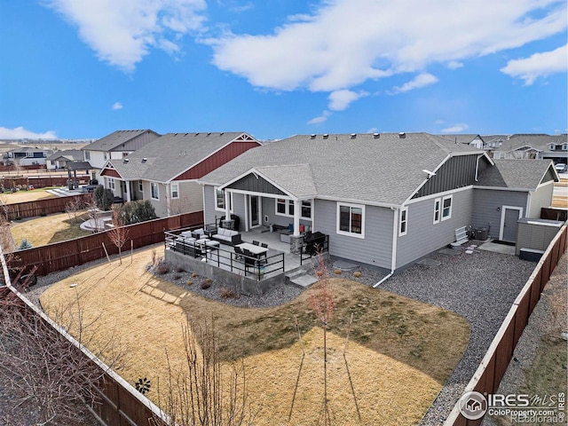 back of house with a residential view, a fenced backyard, an outdoor living space, and roof with shingles