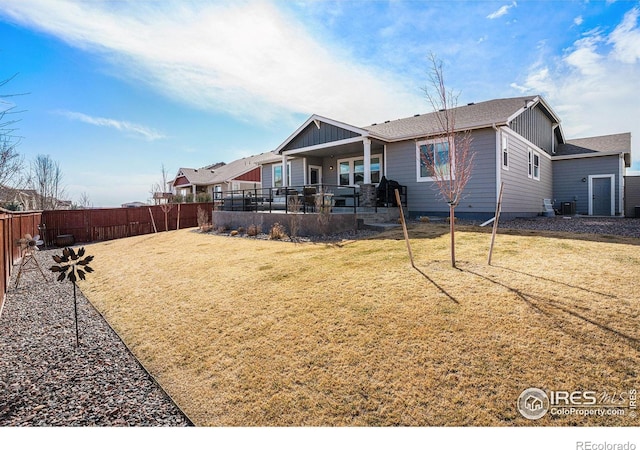 back of house featuring a yard, board and batten siding, a patio area, and a fenced backyard