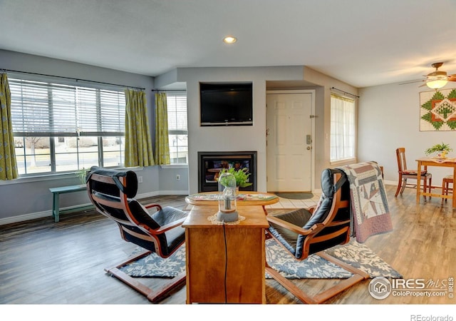 living room with a glass covered fireplace, baseboards, and wood finished floors