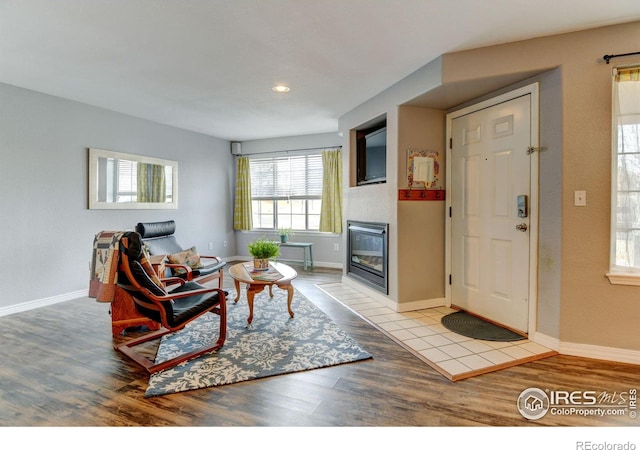 living room with a glass covered fireplace, baseboards, and wood finished floors