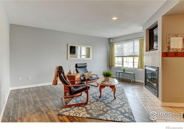 living room with a fireplace with flush hearth, recessed lighting, baseboards, and wood finished floors