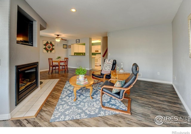 living area featuring wood finished floors, a ceiling fan, baseboards, recessed lighting, and a tile fireplace