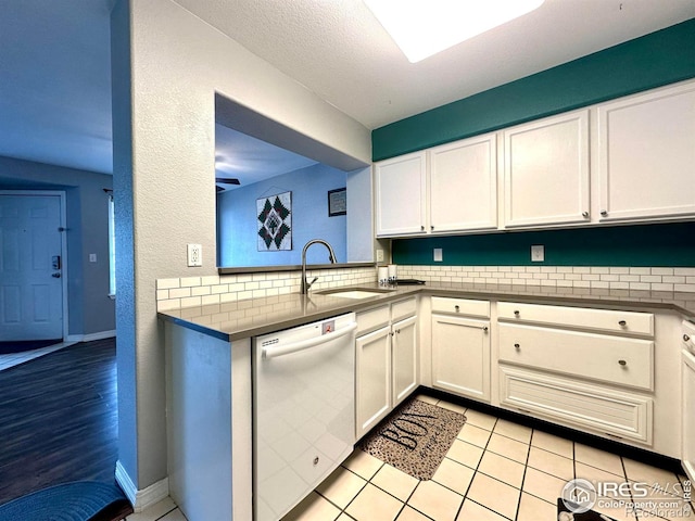 kitchen featuring a sink, white cabinets, white dishwasher, light tile patterned floors, and baseboards