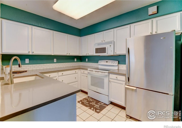 kitchen featuring white appliances, light tile patterned floors, a sink, light countertops, and white cabinetry