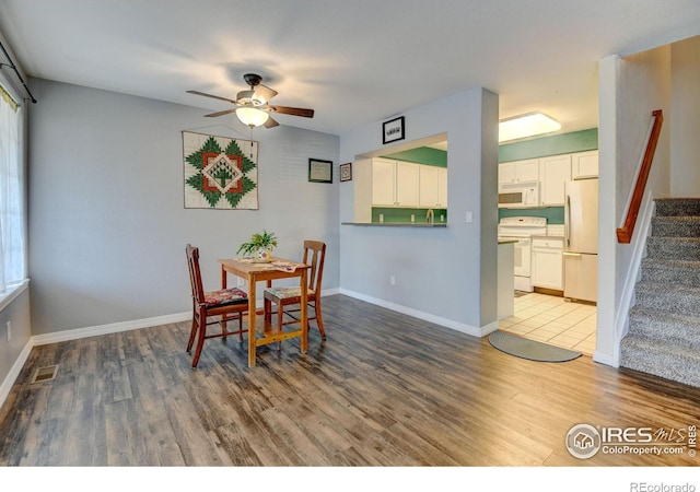 dining space featuring visible vents, a ceiling fan, wood finished floors, stairway, and baseboards