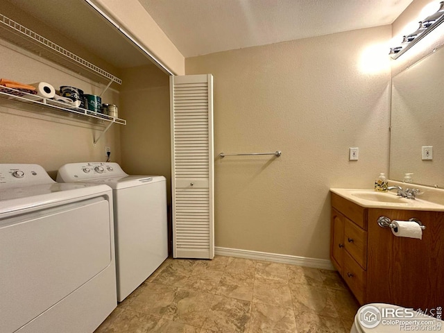 clothes washing area with washing machine and clothes dryer, laundry area, baseboards, and a sink