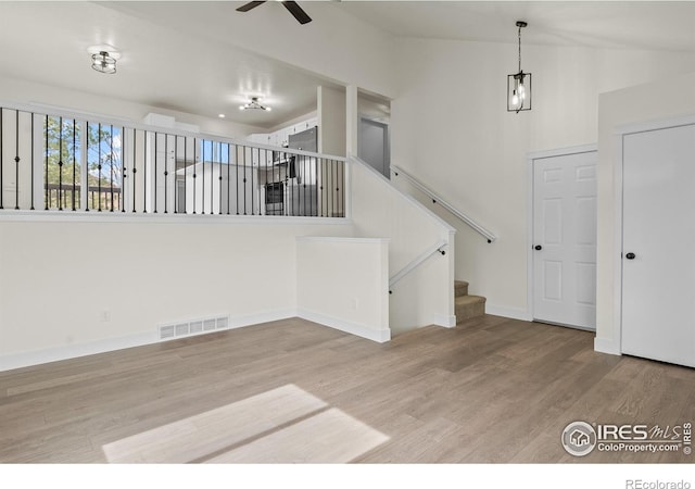 interior space with ceiling fan, wood finished floors, visible vents, baseboards, and stairway