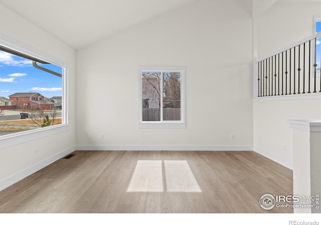 spare room featuring lofted ceiling, baseboards, visible vents, and wood finished floors